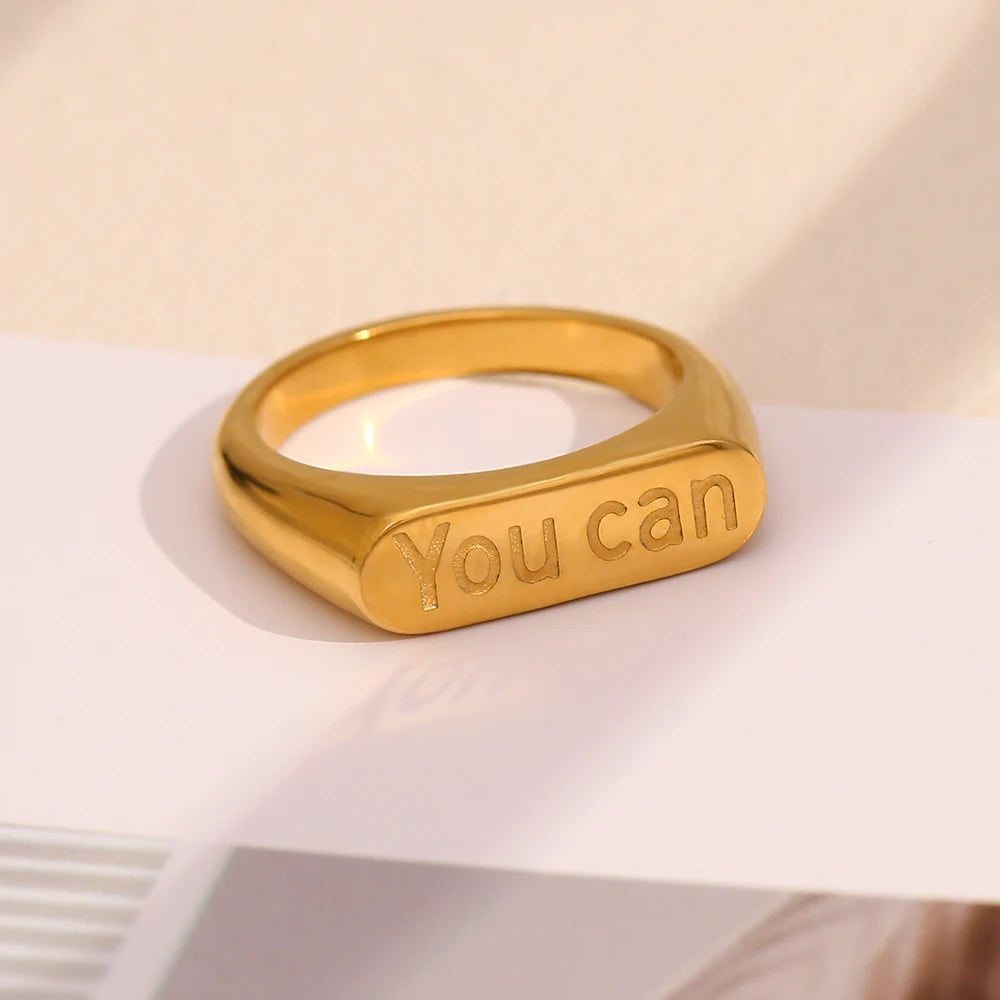 A stainless steel signet ring with the word 'you can' engraved on the top.