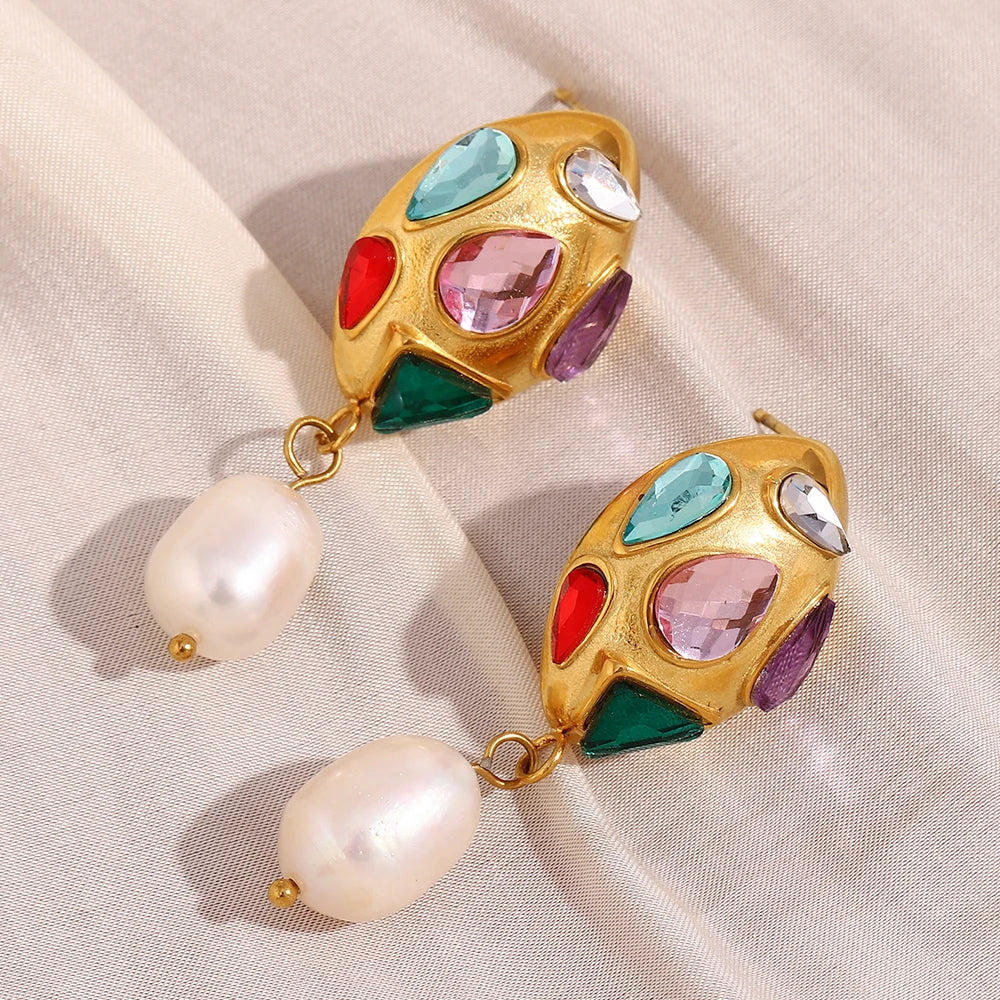 Colorful gemstone earrings with pearl drops on a light fabric background
