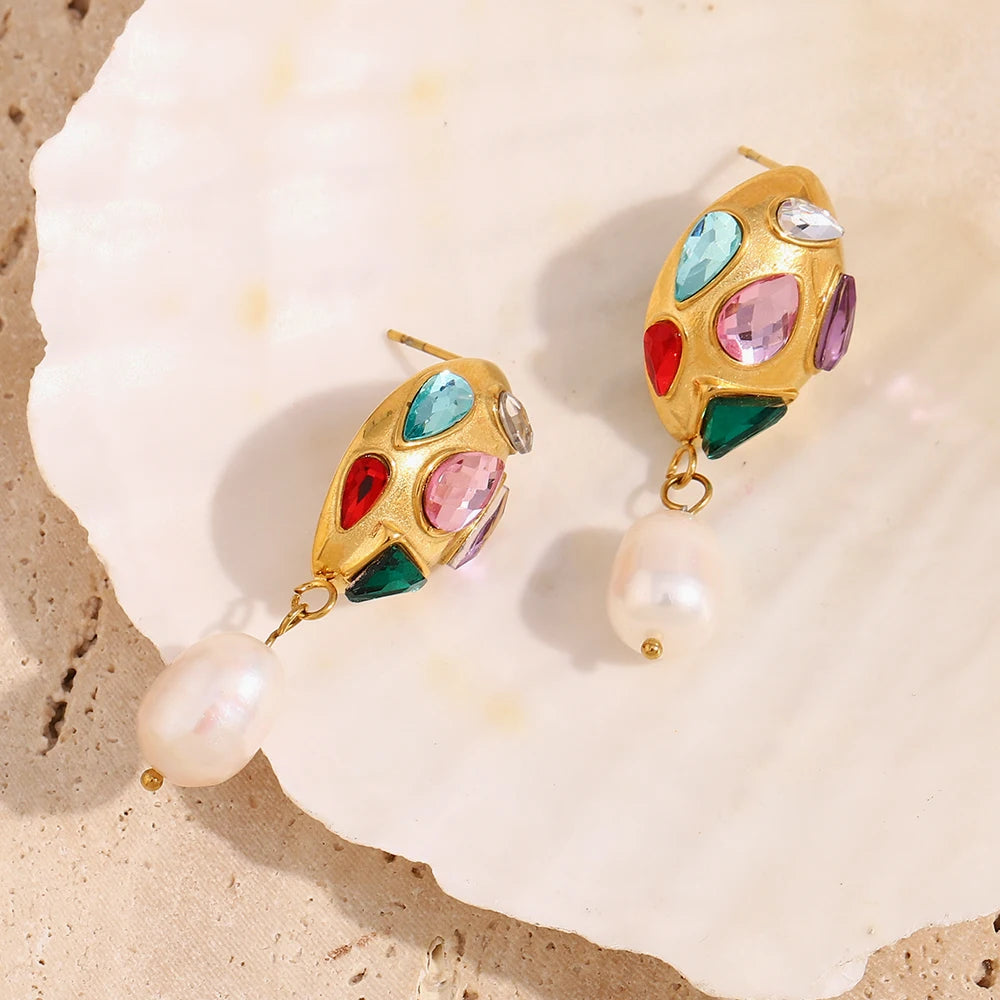 Gold earrings with colorful zirconias and pearls on a shell background
