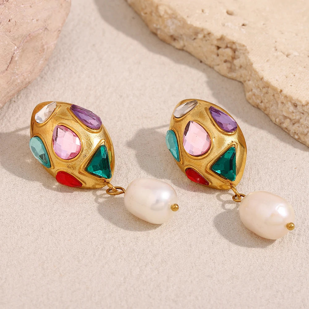 Colorful gemstone earrings with pearl drops on a beige surface