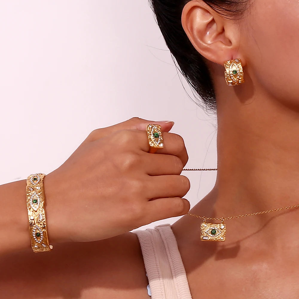 Gold hammered jewelry set including earrings, ring, and bracelet with malachite on a person against a light background