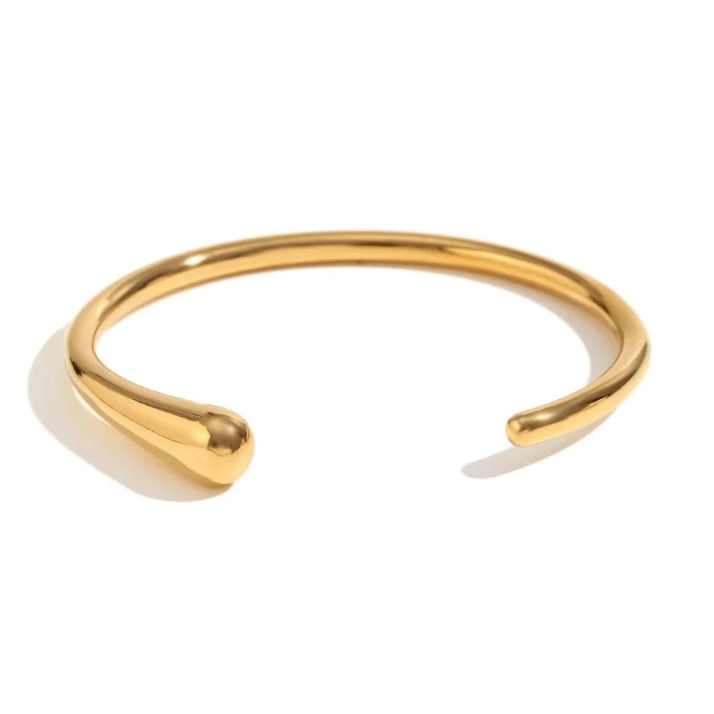 A gold steel bangle bracelet with a sleek, minimalist design, displayed against a white background.