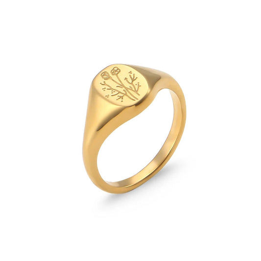Gold signet ring with engraved flower design on a white background