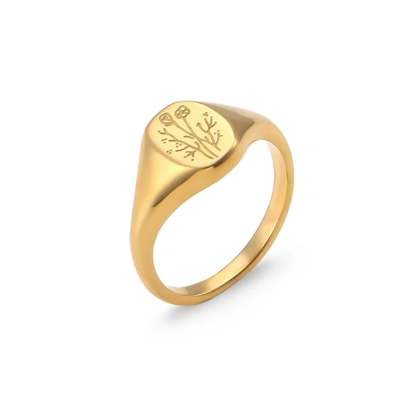 Gold signet ring with engraved flower design on a white background