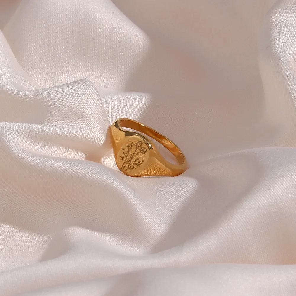 Gold ring with a floral design on a white fabric background