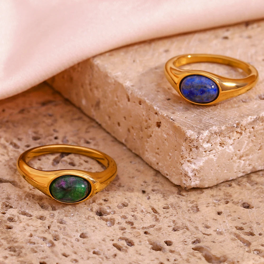 Golden rings with an oval blue or green gemstones set in the center,