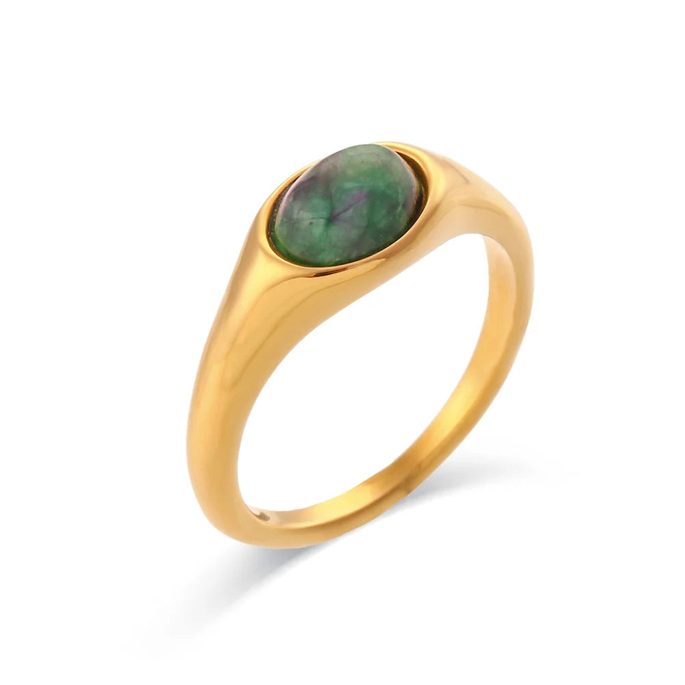 A golden ring with an oval green gemstone set in the center, displayed against a white background.