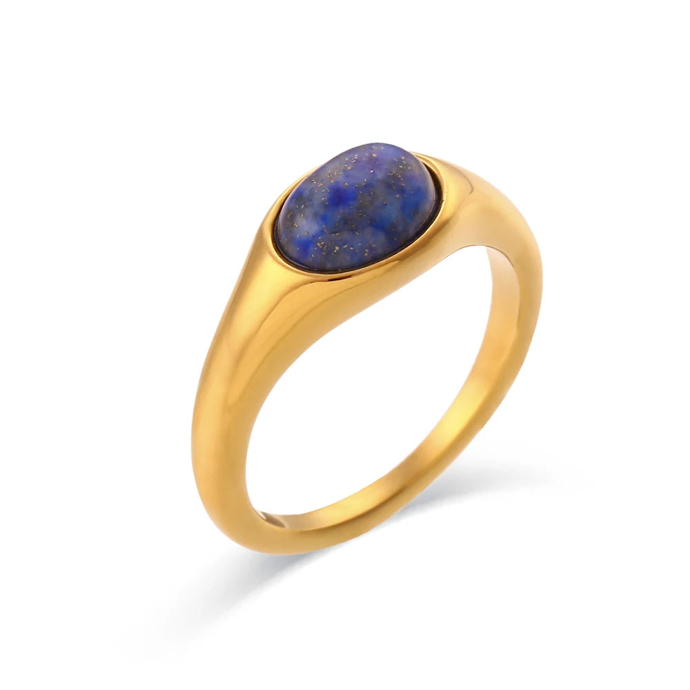 A golden ring with an oval blue gemstone set in the center, displayed against a white background.
