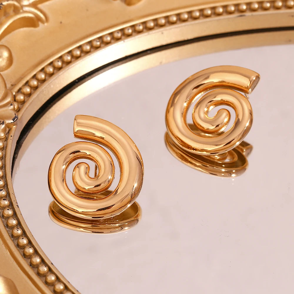 A pair of 18K gold plated stainless steel earrings with a spiral design on a mirror