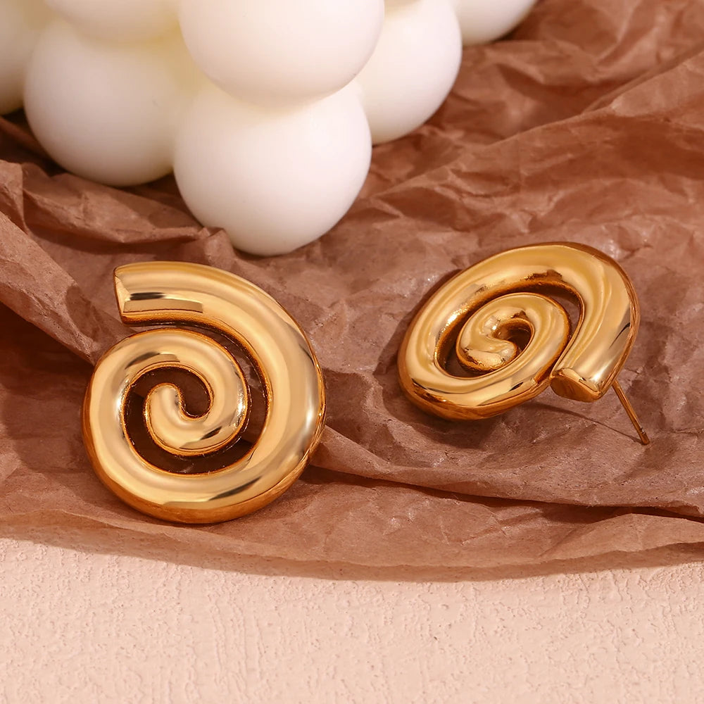 A pair of 18K gold plated stainless steel earrings with a spiral design on paper display