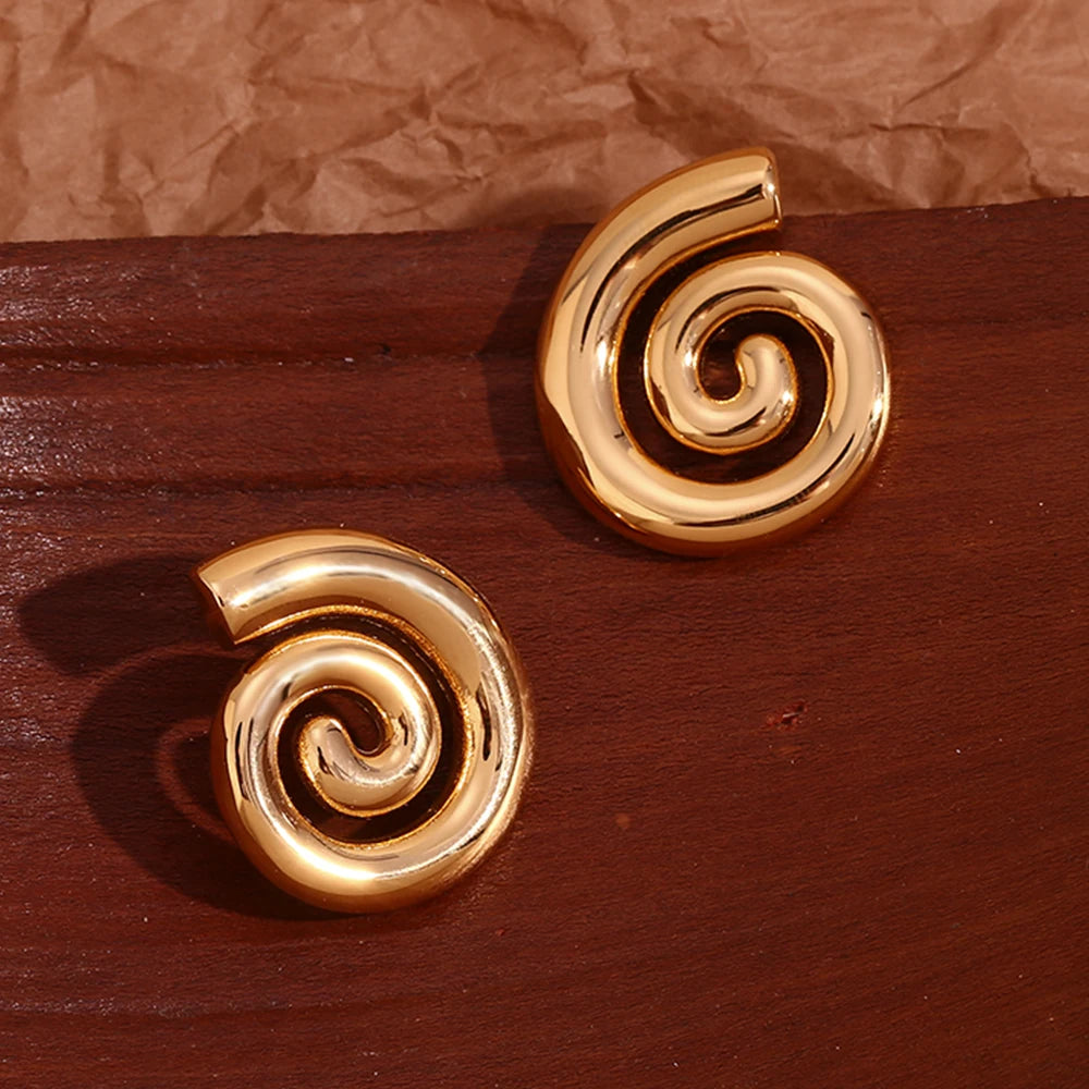 A pair of 18K gold plated stainless steel earrings with a spiral design on wood