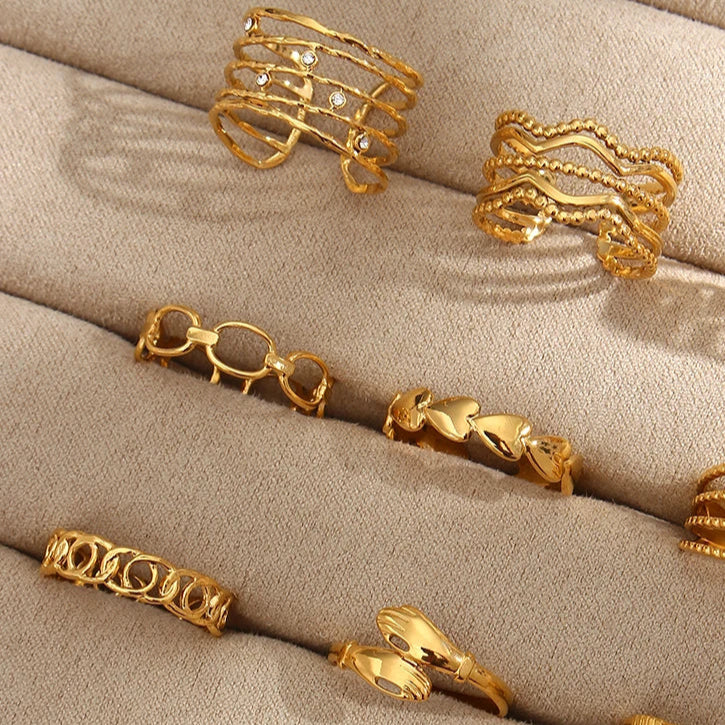 An adjustable gold ring with a minimalist linked design in jewelry display with other rings