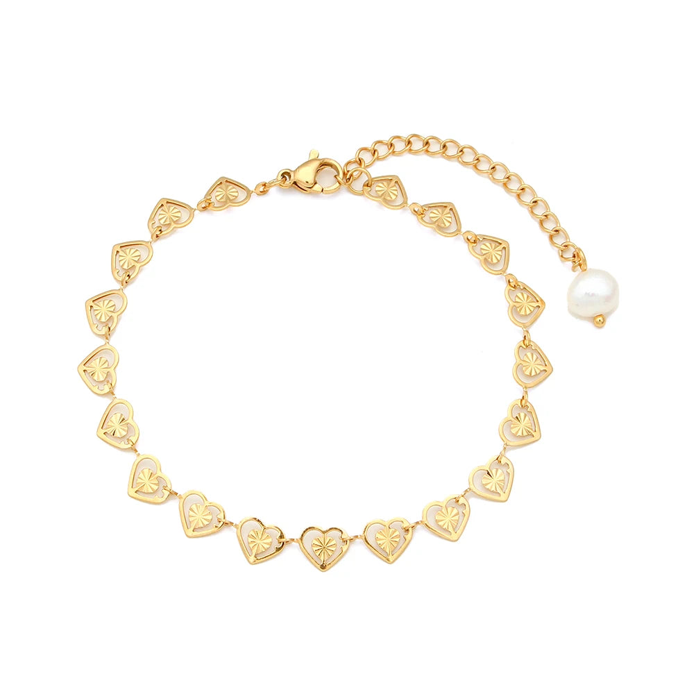 A gold bracelet with heart-shaped links and a natural pearl featured towards the end.
