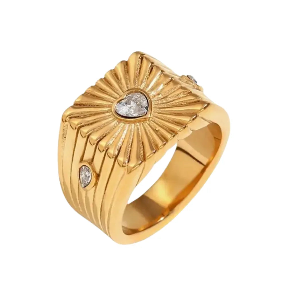 A gold stainless steel signet ring with a geometric design and crystal accents, featuring a prominent heart shaped zirconia at the top.