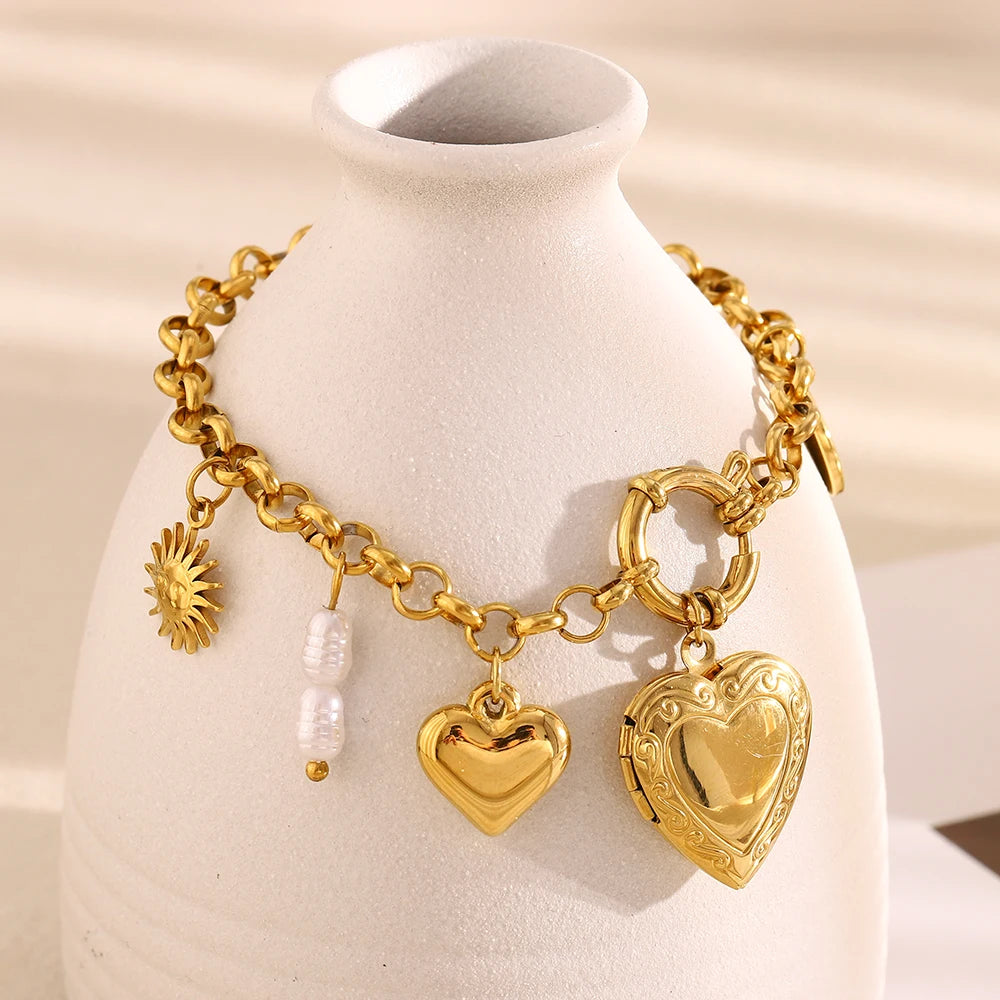 Gold charm braceler with heart-shaped pendants on a white vase