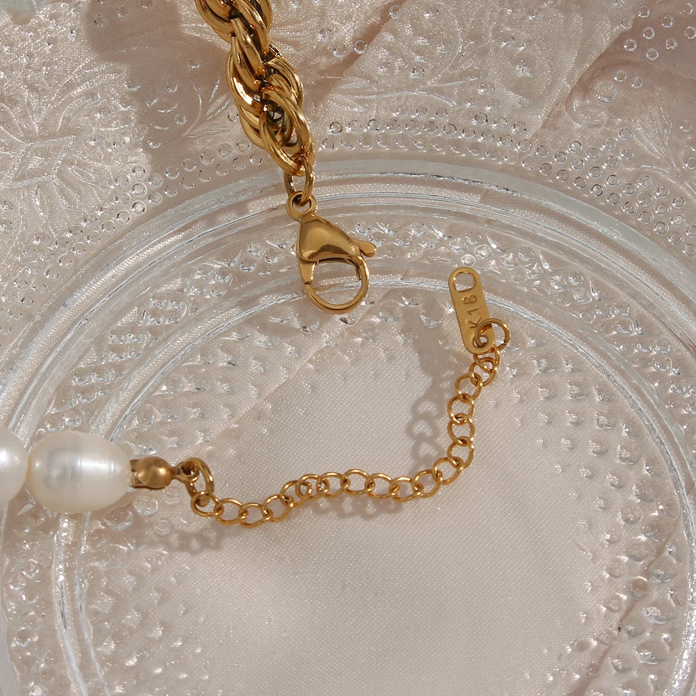 Gold chain bracelet with a pearl on a textured beige background