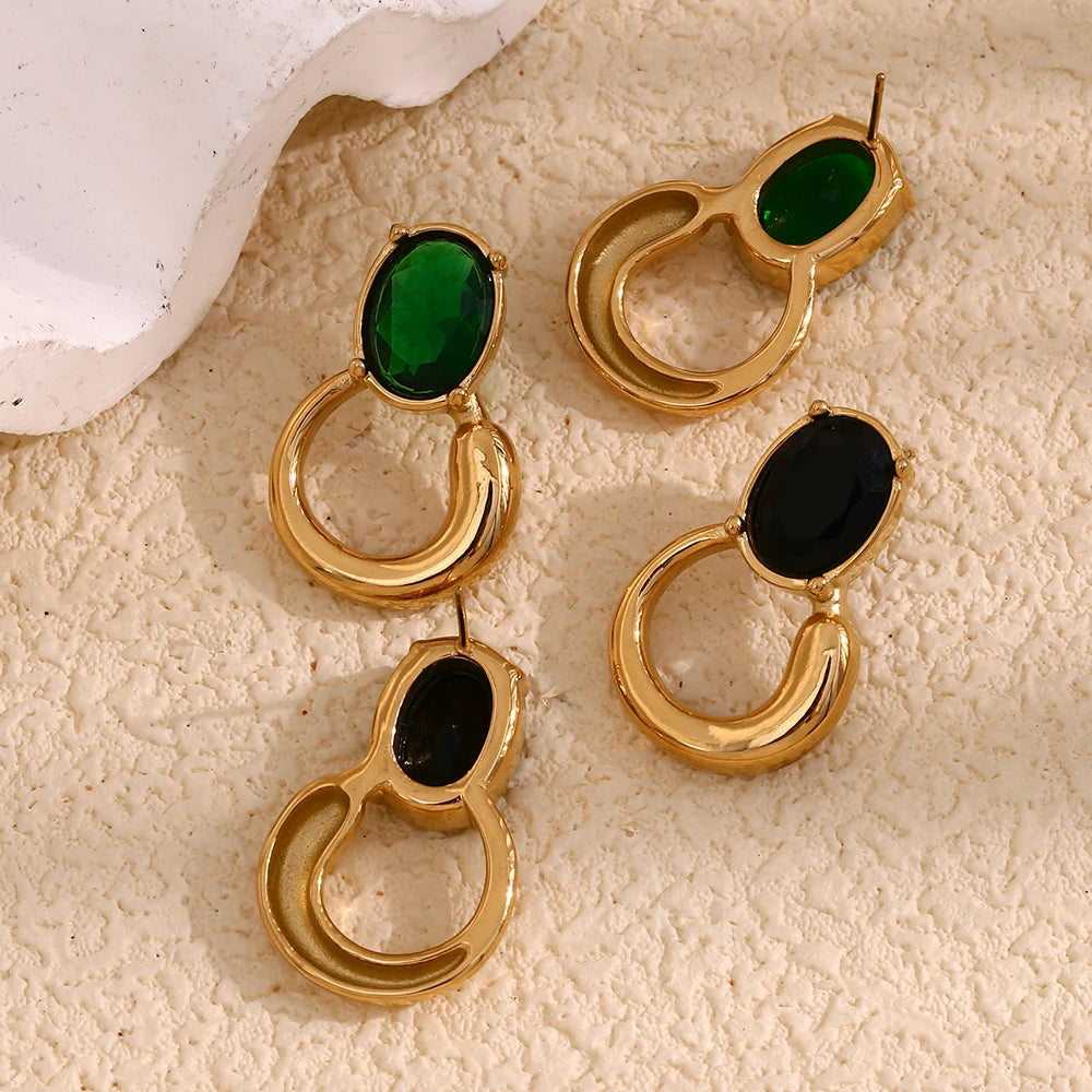 A pair of gold-colored earrings with deep green or black oval stones set in a loop design back side