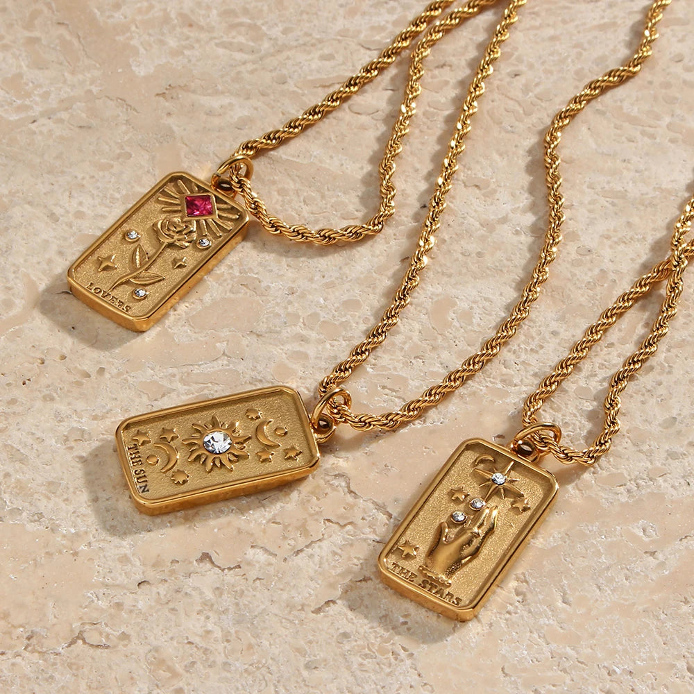 Stainless steel gold necklaces featuring tarot card pendants, displayed on a textured beige tile background.