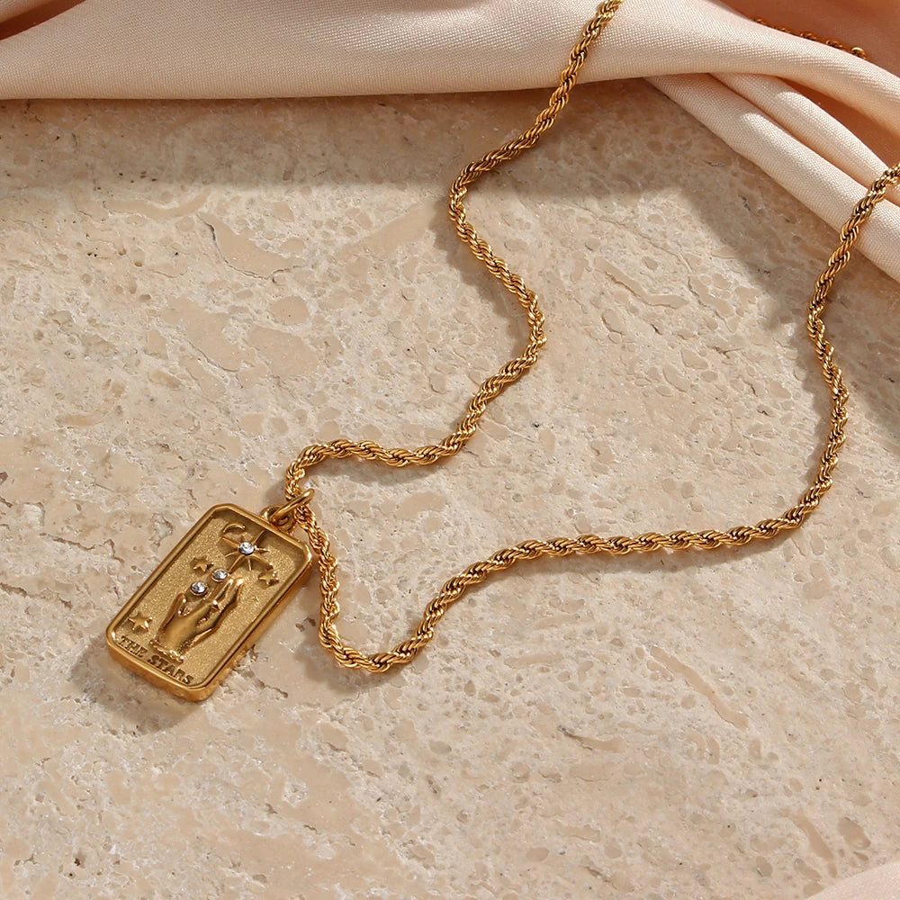 Stainless steel gold necklace featuring tarot card pendant, displayed on a textured beige tile background