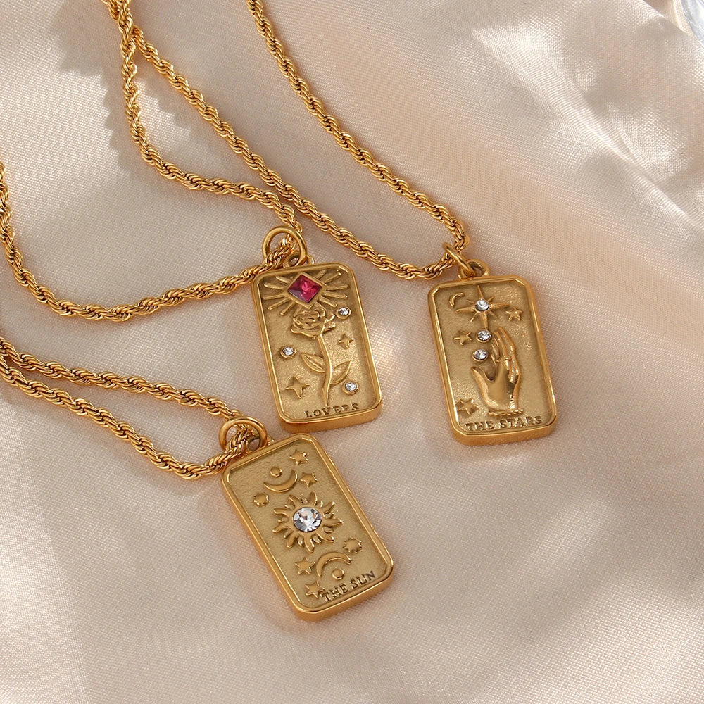 Stainless steel gold necklaces featuring tarot card pendants, displayed on a soft white fabric.