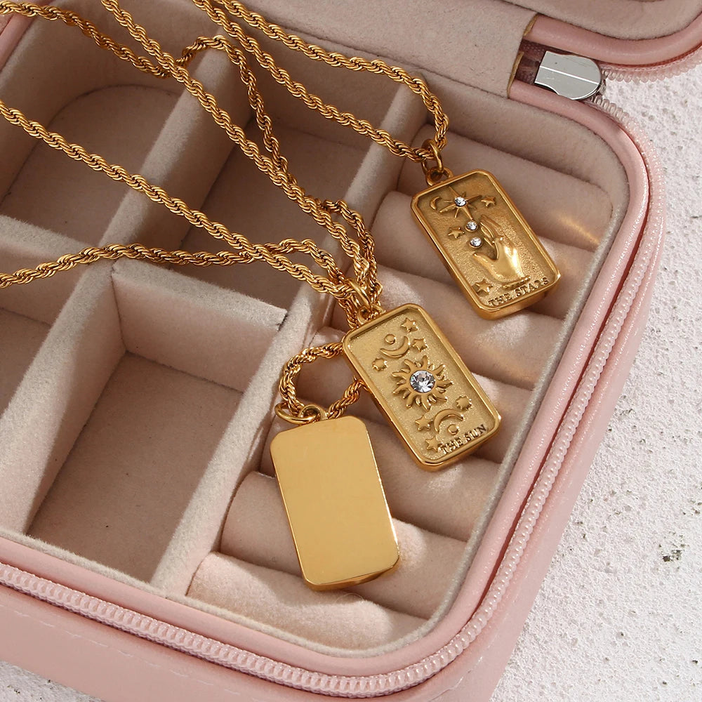 Stainless steel gold necklaces featuring tarot card pendants, displayed on a pink jewelry box.