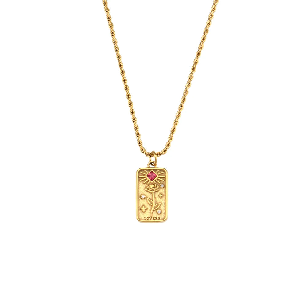 A gold-colored necklace featuring  a tarot card pendant, displayed on a white background.