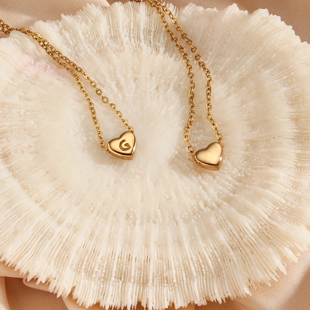 Gold necklace with heart-shaped pendants on a textured beige surface
