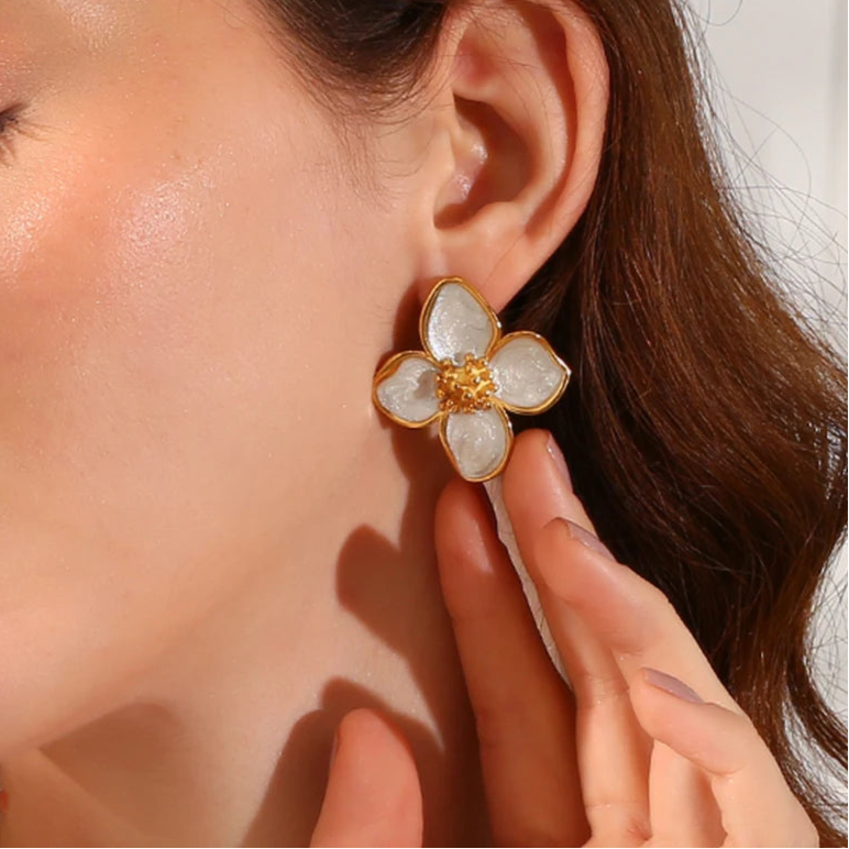 A pair of 18K gold coated floral earrings with white enamel petals on model