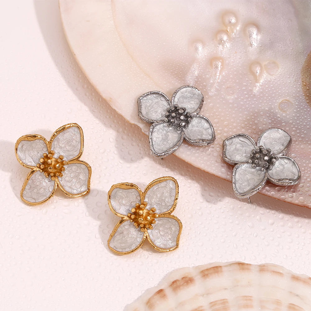 A pair of 18K gold coated floral earrings with white enamel petals sprayed with water