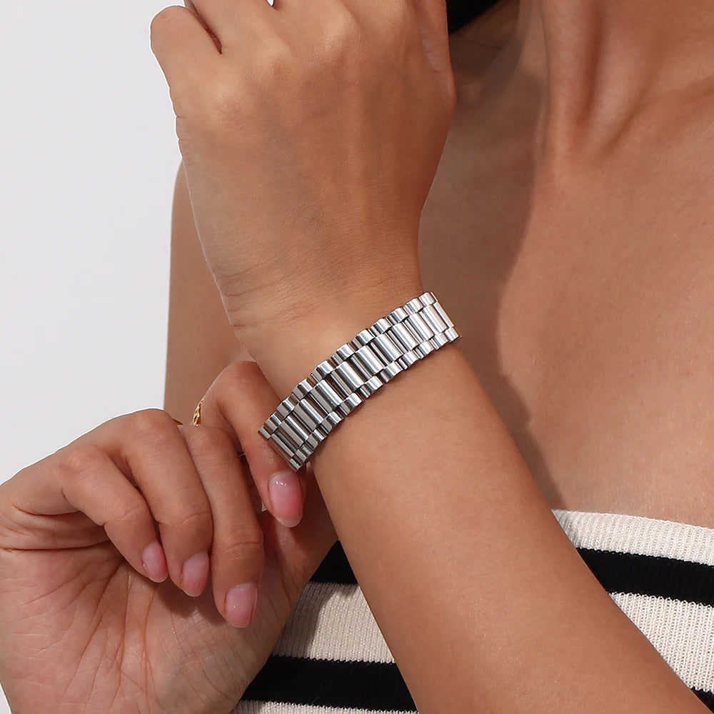 Close-up of a wrist wearing a silver watch band with a neutral background