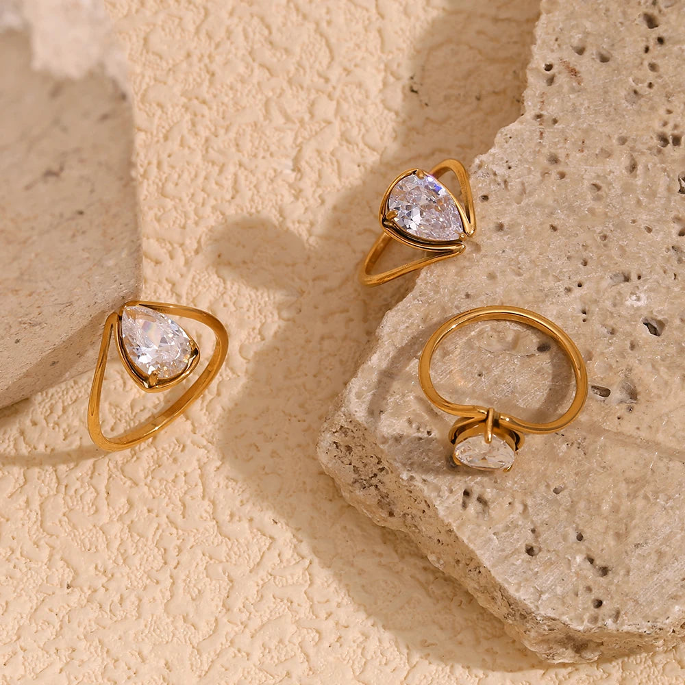 A gold stainless steel ring with a large teardrop-shaped clear zirconia centerpiece.