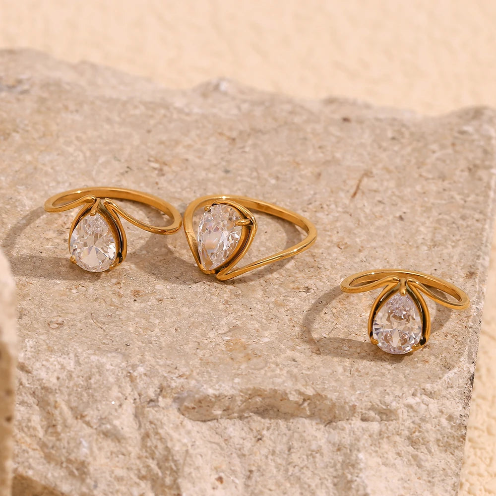 A gold stainless steel ring with a large teardrop-shaped clear zirconia centerpiece.