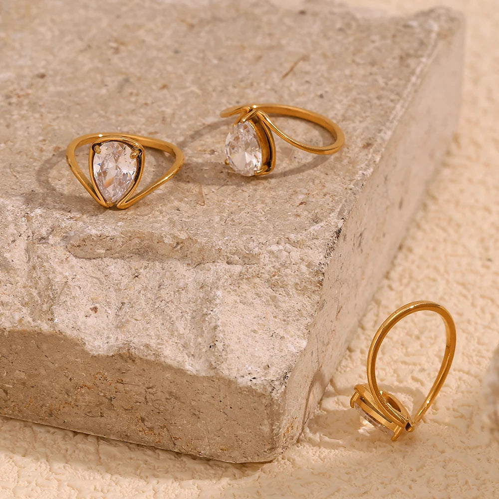 A gold stainless steel ring with a large teardrop-shaped clear zirconia centerpiece.