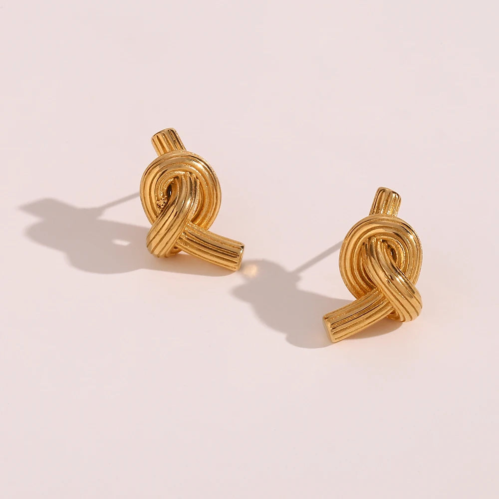 A pair of 18K gold plated stainless steel knot earrings with a textured surface.
