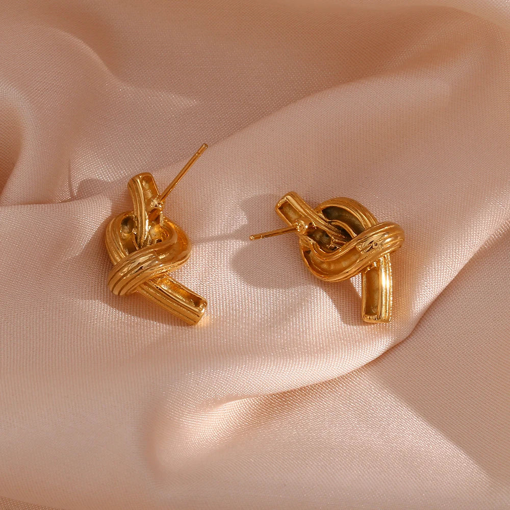 A pair of 18K gold plated stainless steel knot earrings with a textured surface from the backside