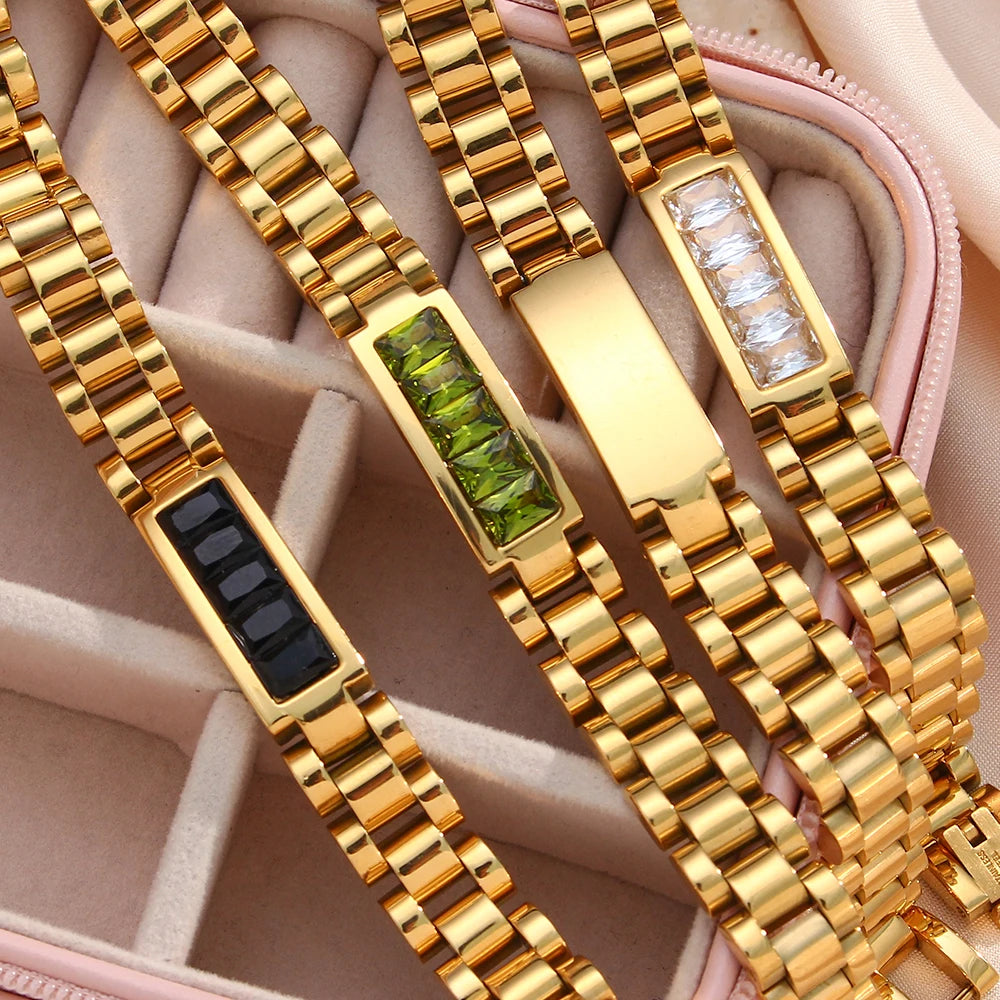 Gold bracelets with gemstone inlays on a pink fabric background