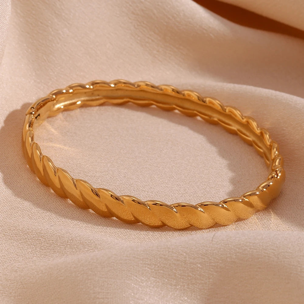 A gold twisted bangle bracelet with a shiny finish.
