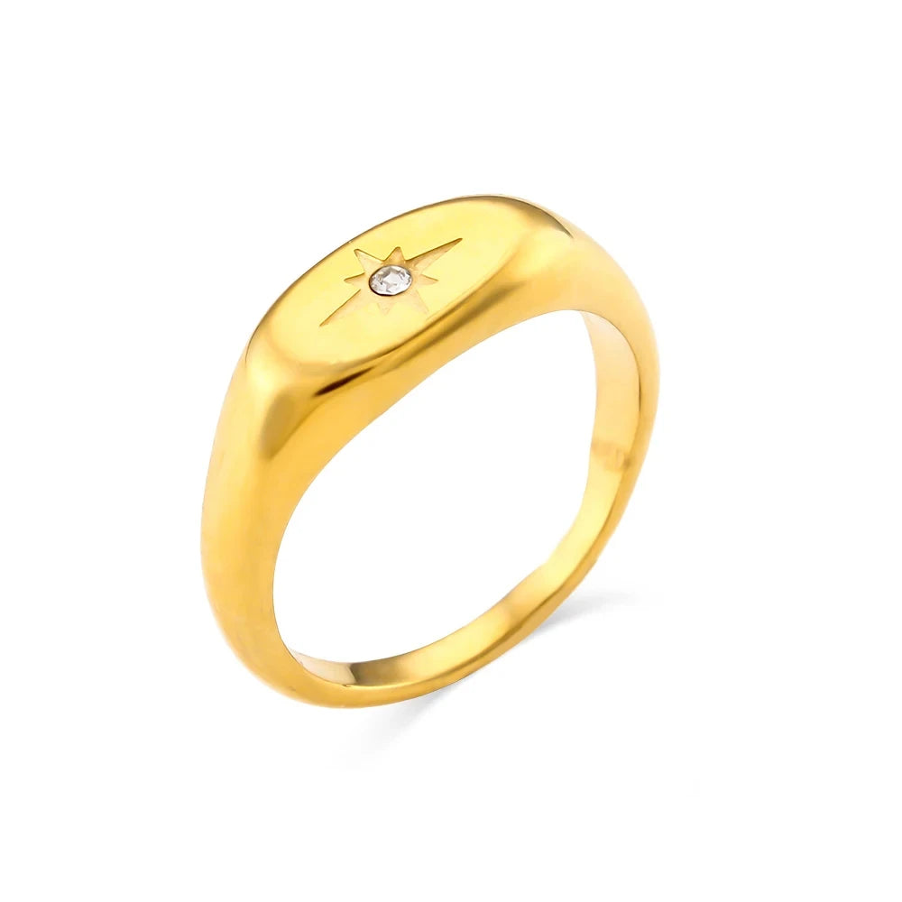 A gold-colored signet ring with a single white diamond on the top, symbolizing the rising star theme.