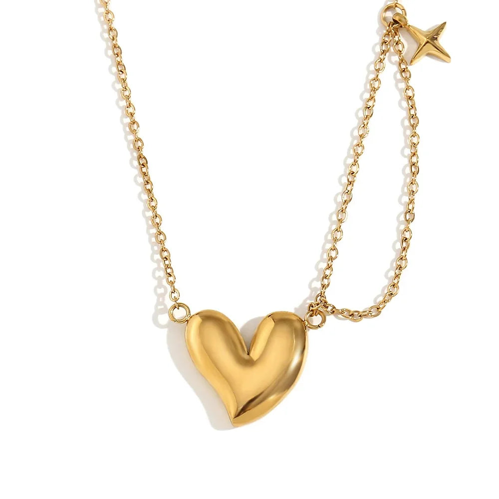 A gold steel necklace with a heart-shaped pendant and a small star charm