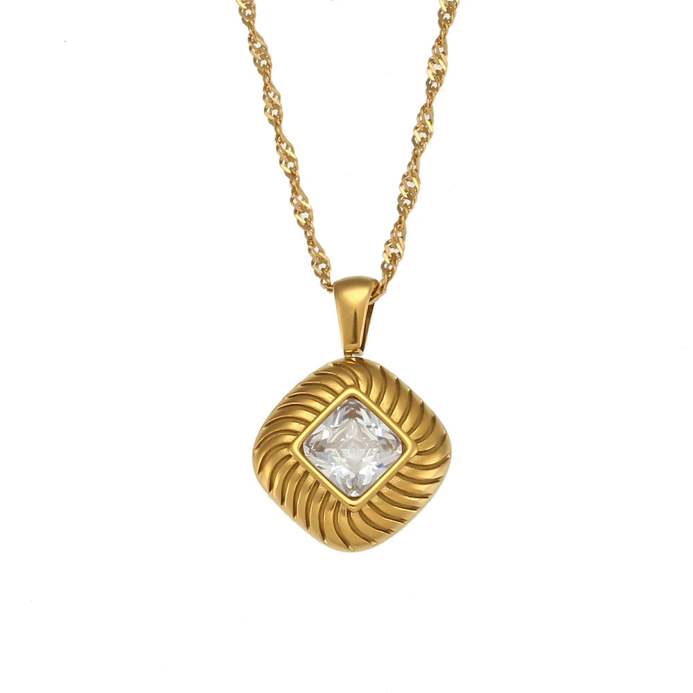 A gold-plated stainless steel necklace with a square pendant featuring a clear crystal, on a white background.