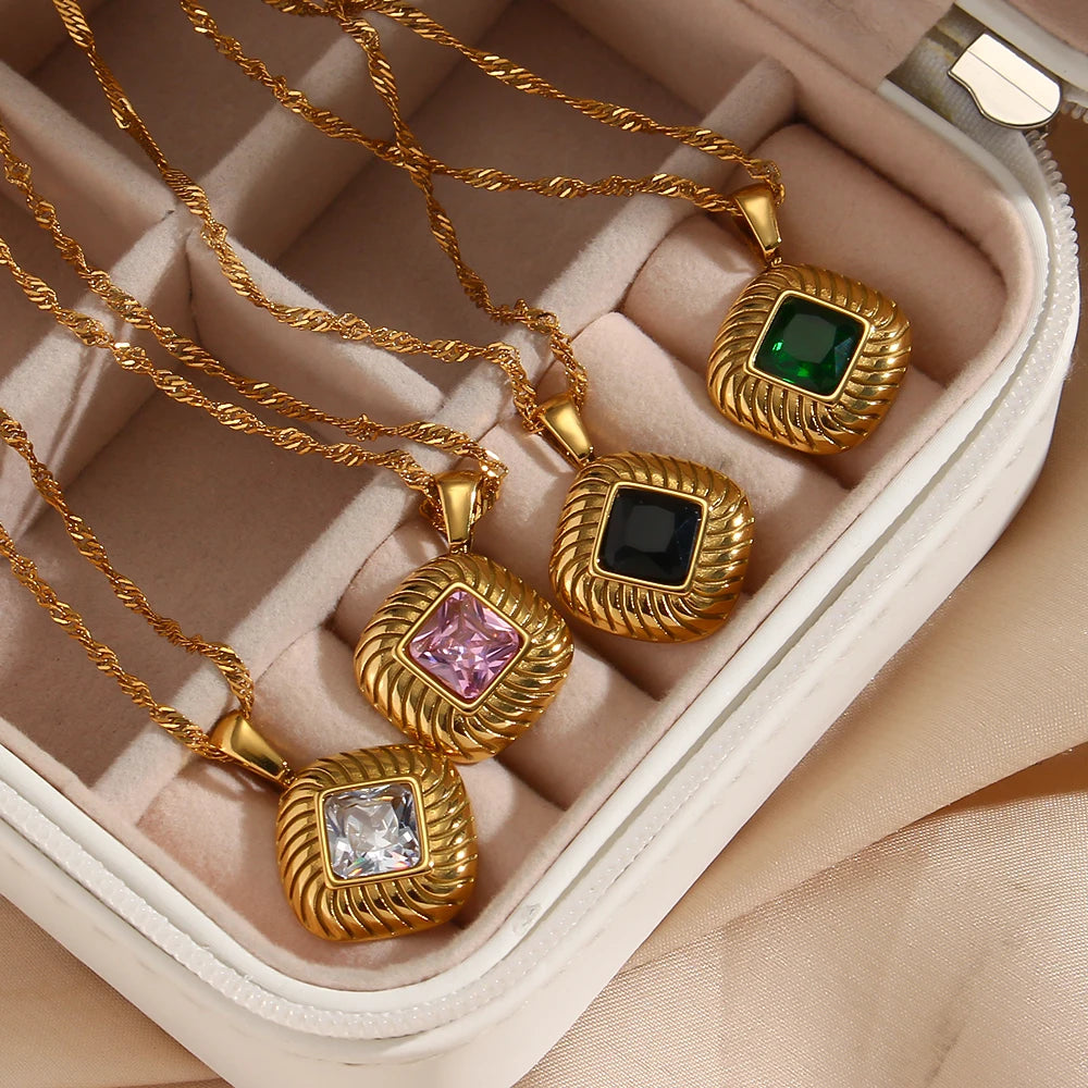 Gold-plated stainless steel necklaces with a square pendant featuring a crystal, on a beige jewelry box