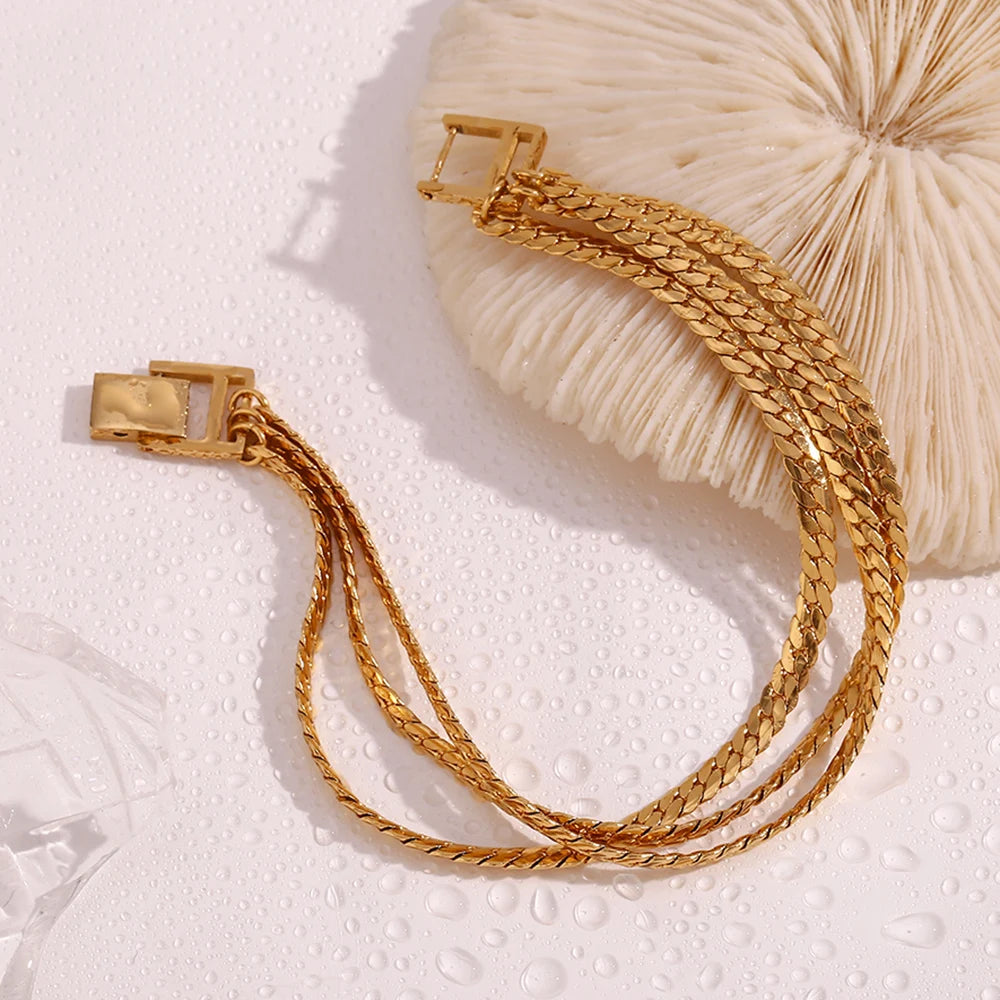 A gold stainless steel bracelet with a triple chain design, featuring a clasp closure.