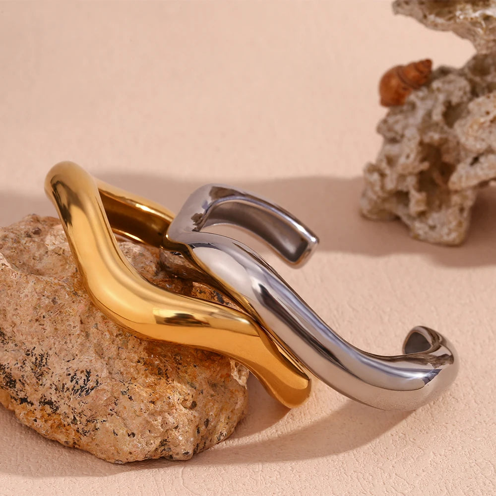 gold and silver Sculpted Bangle Bracelets displayed on rock
