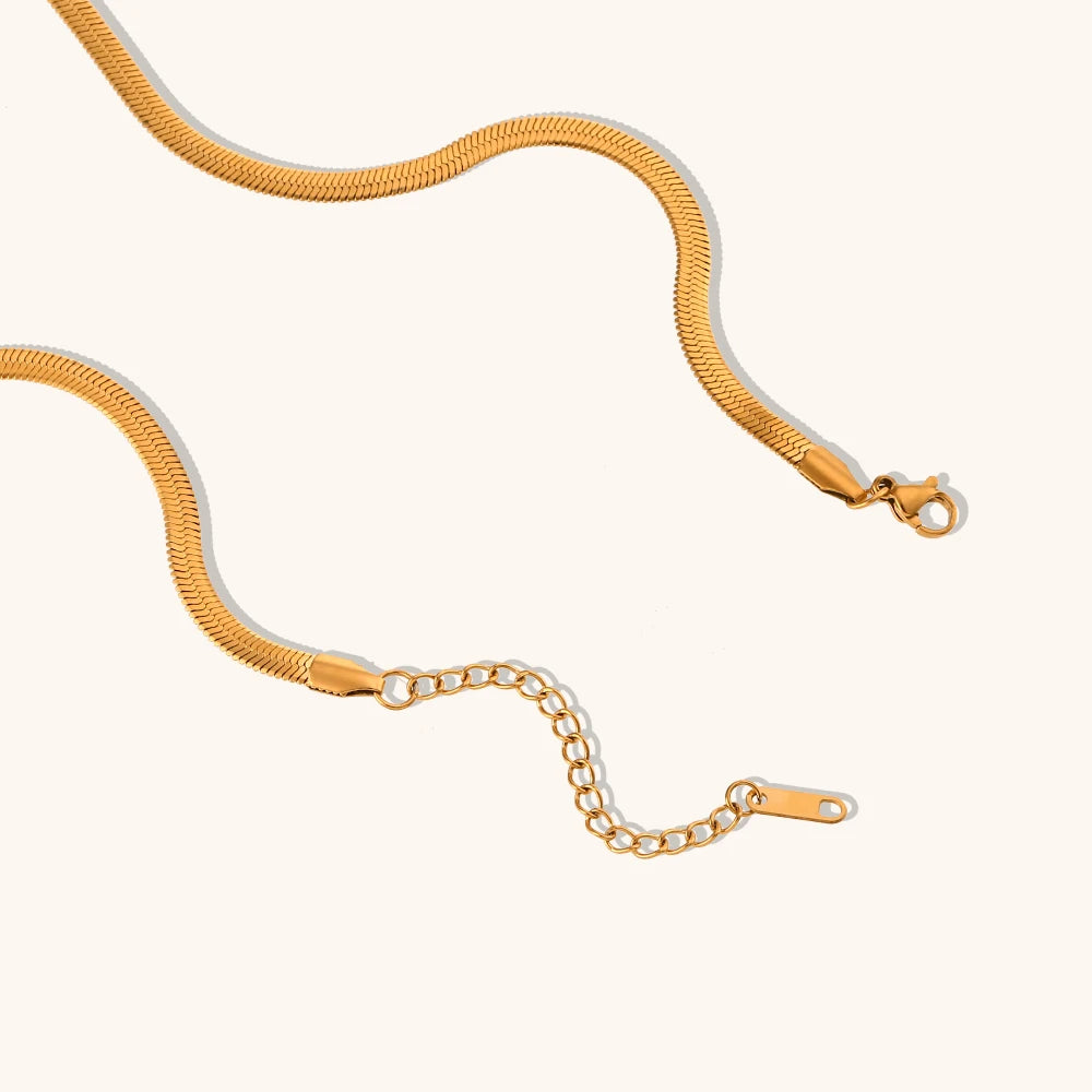 Gold snake chain necklace on a white background