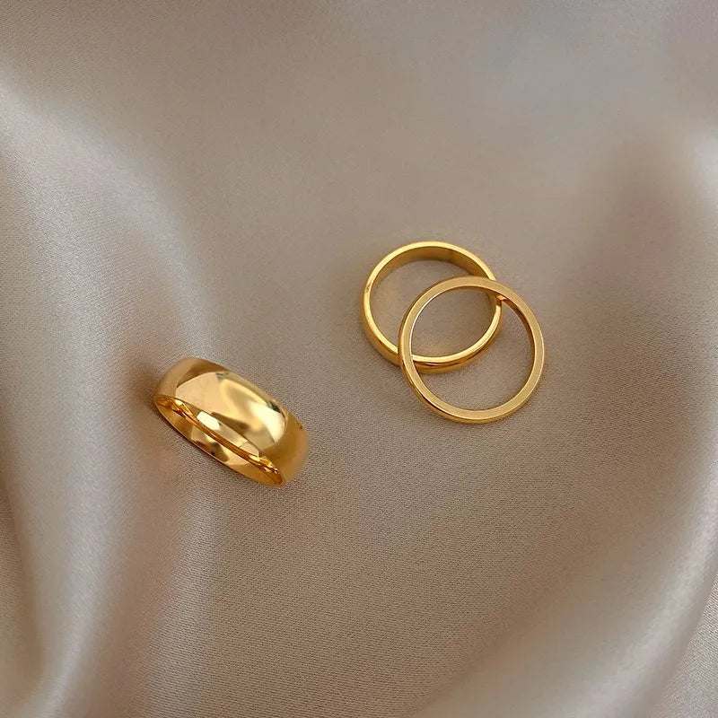 three plain steel gold rings on a beige fabric background