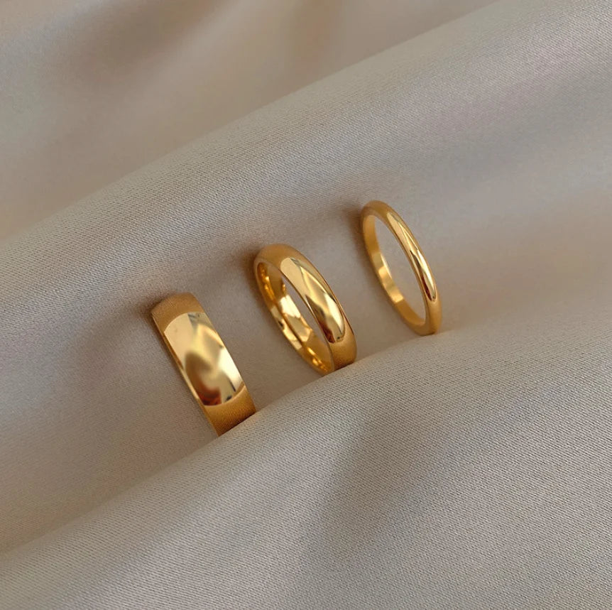 Three gold rings on a beige fabric background