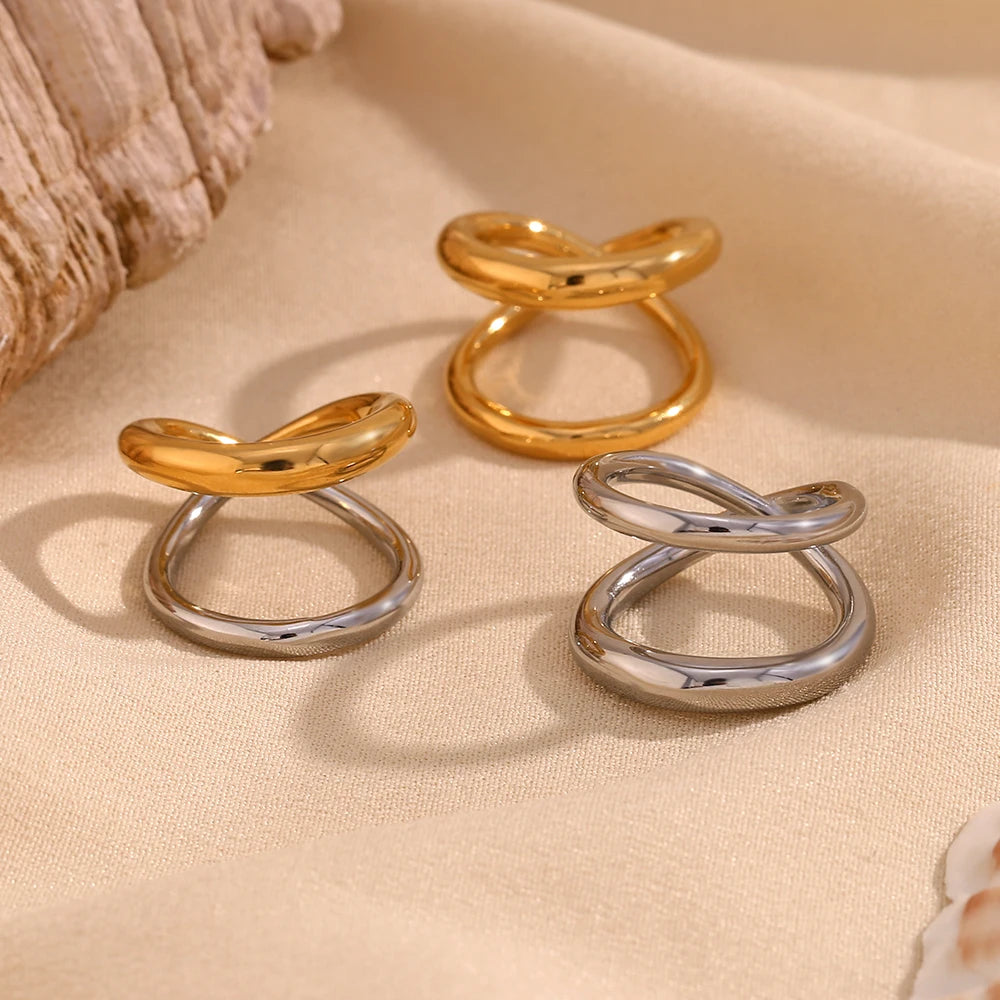Elegant gold or silver, double looped rings with a smooth finish, displayed on a beige fabric.