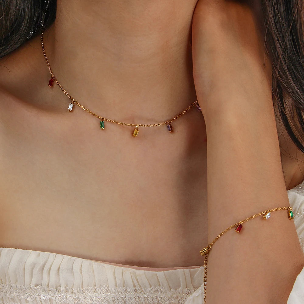 A golden bracelet and necklace with multicolored zirconia charms on a model 