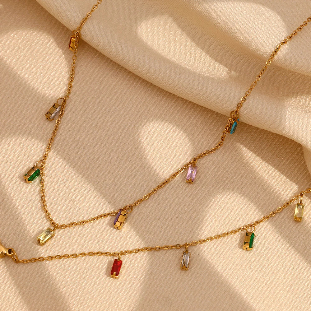 A golden necklace with multicolored zirconia charms attached to a gold chain, 