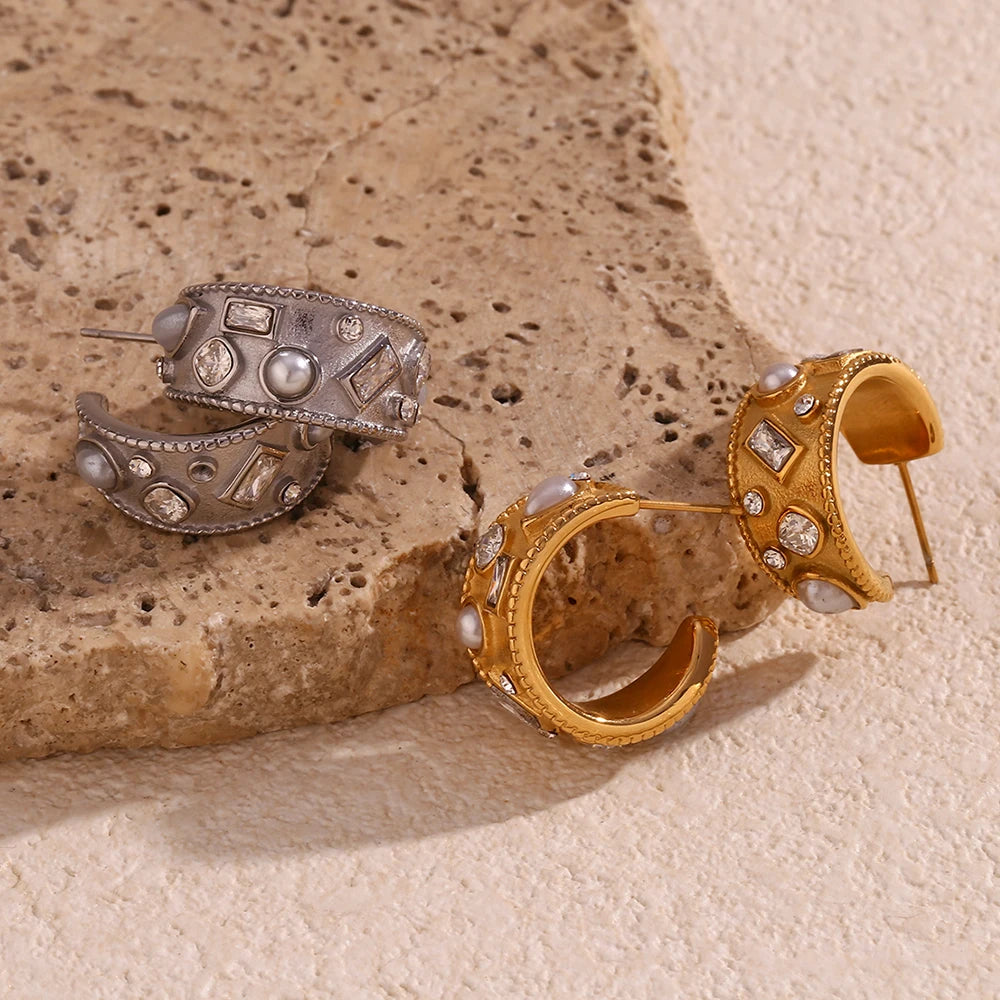 Pair of gold and silver hoop earrings on a textured stone surface